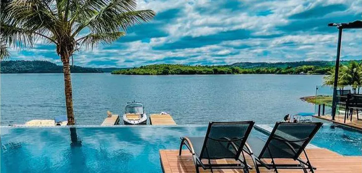 Deck com espreguiçadeiras à beira de piscina com vista para o lago